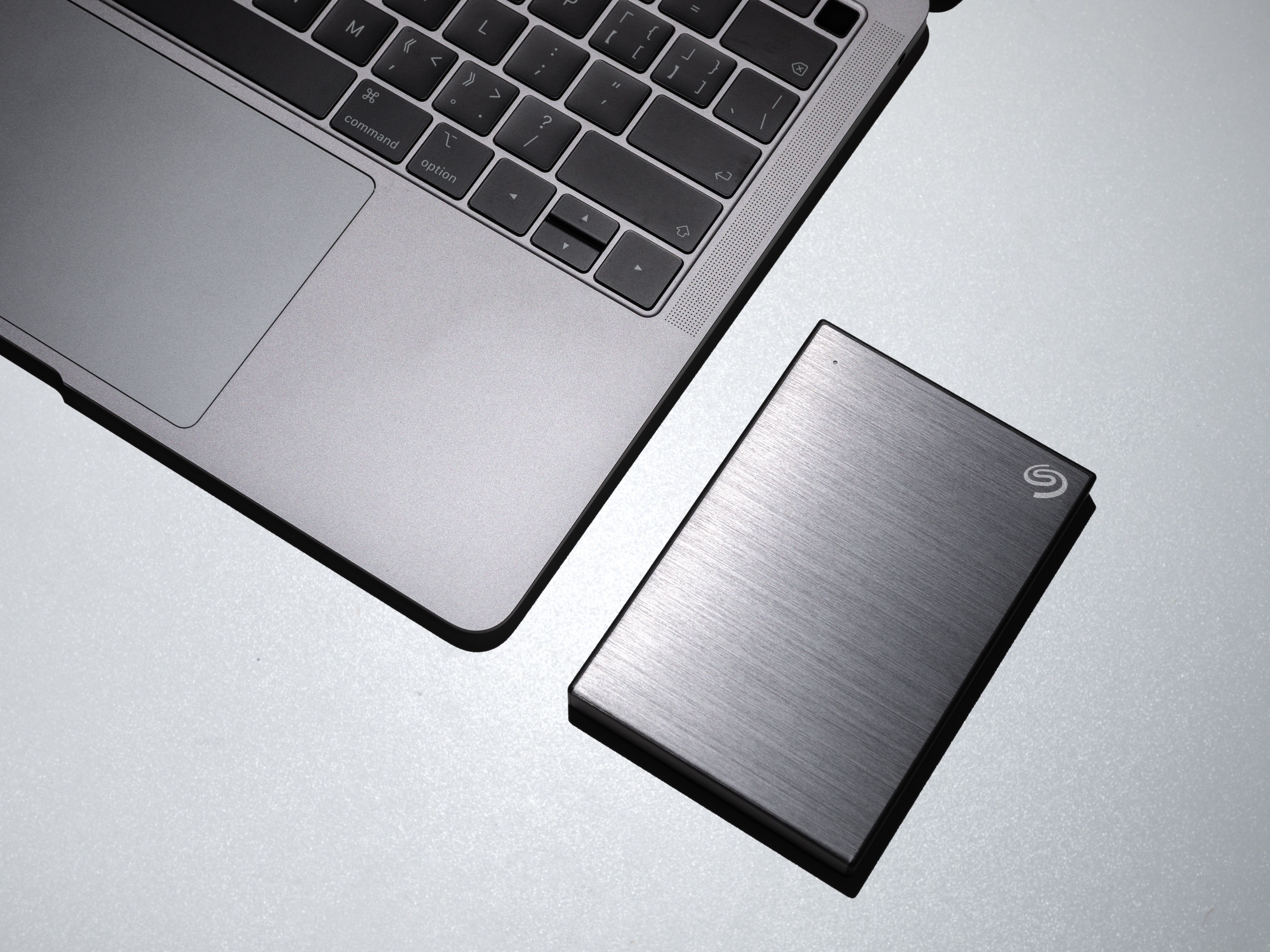 Shows a portable Hard drive and part of a laptop